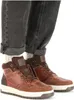 A close-up shot of a person's feet wearing brown leather boots and dark gray jeans. Anteprima dell’immagine prodotto