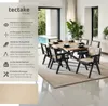 A dining set with chairs and a table in a modern, well-lit room with a pool view. Produktbild-Vorschau