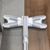 A mop head with a handle is shown on a floor that transitions from tile to wood. Produktbild-Vorschau