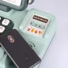 A close-up of a toy cash register with a smartphone placed on it. Produktbild-Vorschau