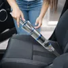 A person is using a handheld vacuum cleaner to clean a car seat. Náhled obrázku produktu