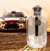 A bottle of perfume is placed in the foreground, with a rally car in the background kicking up dust. Produktbild-Vorschau