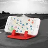 A smartphone is placed on a red silicone stand on a car dashboard, with a road in the background. Produktbild-Vorschau