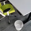 A close-up view of a green office chair next to a white desk and a white mesh waste bin. Produktbild-Vorschau