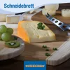 A close-up of a cheese board with various cheeses, grapes, kiwi, and a cheese knife, with the brand logo and product name visible. Produktbild-Vorschau