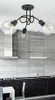 A modern kitchen with a black countertop, dark cabinets, and a grey tiled backsplash. A ceiling light fixture with three clear glass bulbs is visible. Produktbild-Vorschau