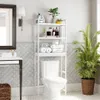 A bathroom scene featuring a toilet with a white shelving unit positioned above it, containing various bathroom essentials and decor. Náhled obrázku produktu