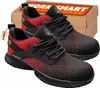 A pair of red and black safety shoes with a cardboard box in the background. Produktbild-Vorschau