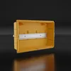 A yellow electrical distribution box with a silver DIN rail mounted inside, set against a dark background. Produktbild-Vorschau