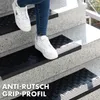 A person's legs and feet wearing white sneakers are shown walking up a set of outdoor stairs. The stairs are covered with black anti-slip mats. Anteprima dell’immagine prodotto