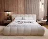 A modern bedroom with a plush boucle bed as the centerpiece, set against a backdrop of wood paneling and vertical slats. Náhled obrázku produktu