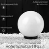 A white spherical lamp is placed on a stone surface surrounded by white gravel, with a dark wooden background. Text overlays describe product features. Náhľad obrázku produktu