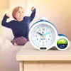 A child is stretching in bed next to an alarm clock. Produktbild-Vorschau