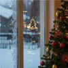 A Christmas tree decorated with ornaments and lights, next to a window with frost and a hanging Christmas tree light. Anteprima dell’immagine prodotto