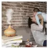 A woman is holding a baby while sitting on a couch next to a humidifier and some books. Podgląd zdjęcia produktu