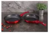 Two red frying pans with black non-stick interiors are placed on a dark gray countertop. A small green plant in a silver pot is visible in the background. Podgląd zdjęcia produktu