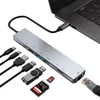 A silver USB hub adapter connected to a laptop, with various cables and memory cards shown around it. Náhled obrázku produktu