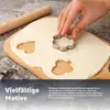A hand is using a flower-shaped cookie cutter on dough, with other cut-out shapes visible. Produktbild-Vorschau