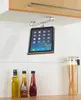 A tablet holder mounted under a kitchen cabinet, with bottles of oil and sauce on the counter below. Produktbild-Vorschau