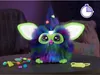 A Furby toy with glowing ears and colorful fur, sitting on a table with accessories. Podgląd zdjęcia produktu