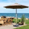 An outdoor patio scene with a large umbrella, chairs, and a table set up near the ocean. Voir les images du produit