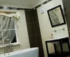 A modern bathroom with a bathtub, sink, and mirror, featuring striped tiling. Anteprima dell’immagine prodotto