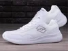 A pair of white Lotto sneakers on a wooden surface with a brick wall in the background. Produktbild-Vorschau