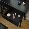 A close-up view of an open drawer in a black vanity table, revealing makeup items inside. Voir les images du produit