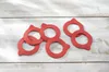 Several red rubber sealing rings are scattered on a white wooden surface. Produktbild-Vorschau