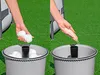 Two side-by-side images showing a person adding items to a gray bucket. The left image shows white balls being added, and the right image shows white granular material being added. Produktbild-Vorschau