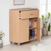 A wooden sideboard with a drawer and two doors, placed in a room with plants and a window. Náhľad obrázku produktu