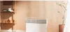 A white Xiaomi MI Smart Space Heater S is placed on the floor next to a shelf with decorative items and a potted plant in a room with light peach walls. Produktbild-Vorschau