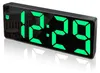 A digital alarm clock with a black casing and green LED display showing the time 12:29. The clock has a reflective surface and is shown on a reflective surface, casting a shadow. Produktbild-Vorschau
