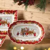Christmas-themed oval platter with Santa and children depicted, set against a wooden background with festive greenery. Náhľad obrázku produktu