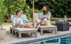A couple relaxing on lounge chairs by a pool. Voir les images du produit