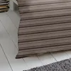 A close-up view of a striped duvet cover and a portion of a rug on a wooden floor. Produktbild-Vorschau