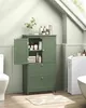 A green bathroom cabinet is shown in a bathroom setting with a toilet and bathtub visible. Náhled obrázku produktu