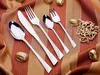 A set of silverware laid out on a striped fabric with decorative walnuts and a golden ornament. Voir les images du produit