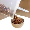Cereal being poured from a clear plastic container into a gray bowl. Produktbild-Vorschau