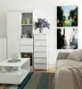 A modern living room with a white dresser and bookshelf, a coffee table, and abstract art on the wall. Produktbild-Vorschau