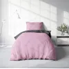 A pink and anthracite duvet cover set is displayed on a bed in a room with a white brick wall and a floor lamp. Produktbild-Vorschau