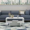 A white coffee table with decorative items and books sits in front of a blue sofa, with a cactus-themed mural on the wall behind it. Anteprima dell’immagine prodotto