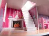 Interior view of a dollhouse with a staircase, fireplace, and furniture. Voir les images du produit