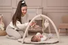 A mother is playing with her baby on a play mat with an activity gym. Produktbild-Vorschau
