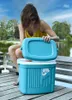 A woman is opening a cooler box next to a lake. Voir les images du produit