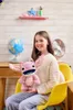 A young girl is sitting on a yellow chair, holding a pink plush toy. The background shows a shelf with decorations and a globe. Náhľad obrázku produktu