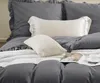 A close-up view of a bed with gray bedding and pillows. Podgląd zdjęcia produktu