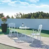 A white bistro set with a table and two chairs on a wooden deck with a potted plant and a wall in the background. Produktbild-Vorschau
