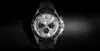 A close-up studio shot of a men's chronograph watch against a dark, textured background. Produktbild-Vorschau