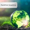 A green globe with continents visible, surrounded by green foliage and dark soil, with a sunburst effect. Produktbild-Vorschau